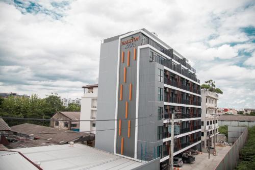 a tall white building with an orange stripe on it at Hallton Hotel Bangkok in Bangkok