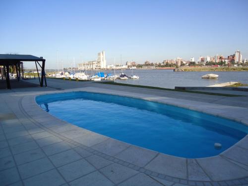 a swimming pool next to a river with boats at Puerto Amarras Hotel & Suites in Santa Fe