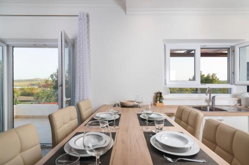 a dining room with a table and a kitchen with windows at Solymar in Posedarje