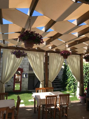 a patio with white tables and chairs under awning at Çona Butik Otel in Alacati