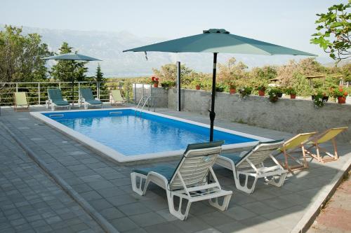 una piscina con due sedie e un ombrellone di Apartman Ana a Radovin