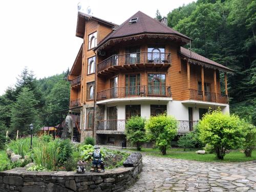 a large wooden house with a garden in front of it at Hotel Dykyi Med in Tatariv