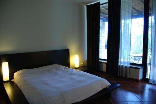 a bedroom with a bed and two lamps and a balcony at Villa con piscina in Canale Monterano