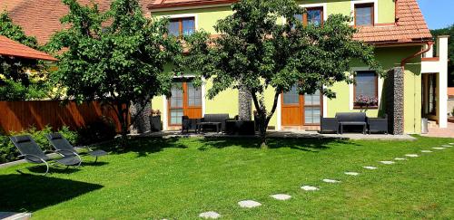 a yard with chairs and trees in front of a house at Třeboňské Apartmány in Třeboň