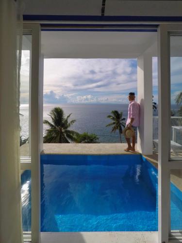 a man standing on a balcony looking out at the ocean at Bintana Sa Paraiso in Mambajao