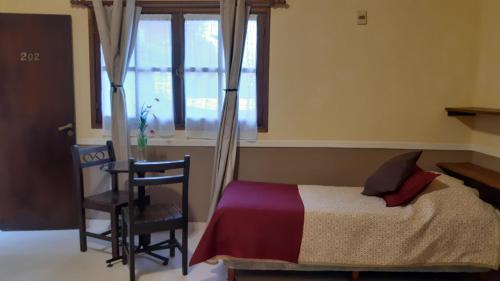a bedroom with a bed and a chair and a window at Hotel Rivera in Colonia del Sacramento