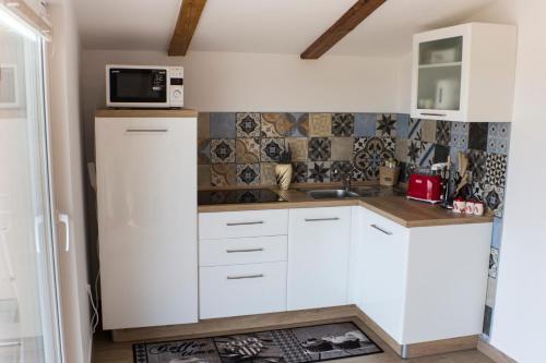 a small kitchen with white cabinets and a microwave at Red Rose Apartment in Portorož