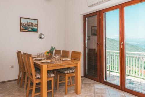 a dining room with a table and chairs and a balcony at Apartments Micic in Lovran