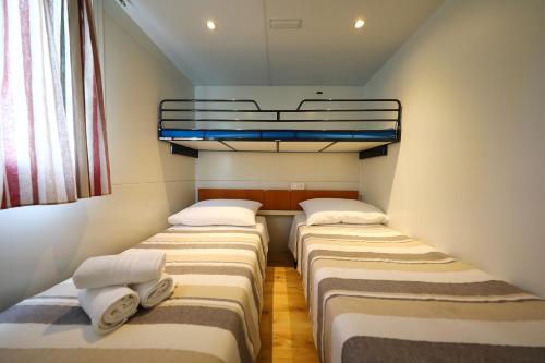 a row of three beds in a small room at Mobile Home Grbe in Nin
