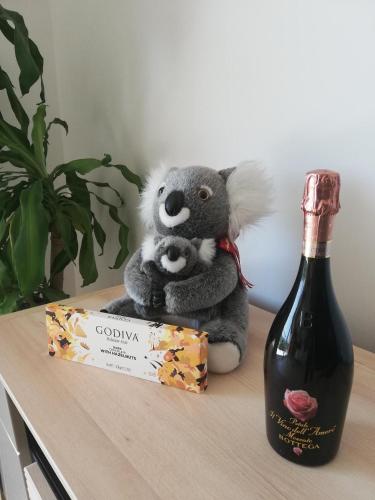 a stuffed koala sitting on a table next to a bottle of wine at Red Rose Apartment in Portorož