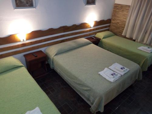 a hotel room with three beds with towels on them at Dennisse Hotel in Victoria
