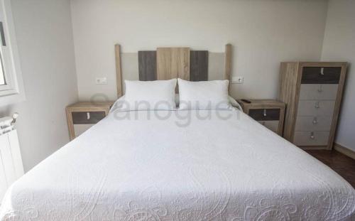 a bedroom with a white bed with two night stands at Pensión CHE in O Pedrouzo