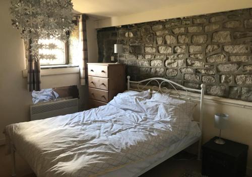 a bedroom with a bed and a stone wall at Halstead Green Farm in Hebden Bridge