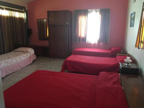 a hotel room with two beds and red sheets at Departamento Carlos paz in Villa Carlos Paz