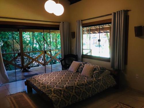 a bedroom with a bed and a large window at Aldeia do Bambu Camping e Chalés in Quartéis