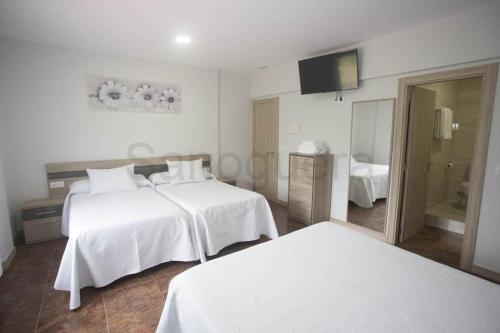 a hotel room with two beds and a television at Pensión CHE in O Pedrouzo