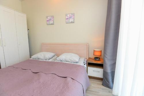 a bedroom with a bed with a purple blanket and a table at For you in Palanga