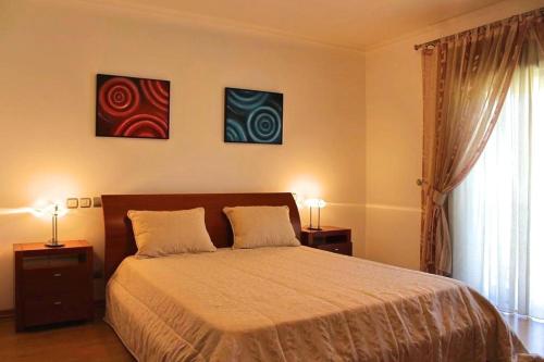 a bedroom with a bed with two lamps and two paintings at Apartamento RH in Nazaré