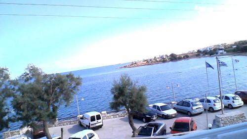 a group of cars parked in a parking lot by the water at Paros Carmel studio-apartment in Logaras