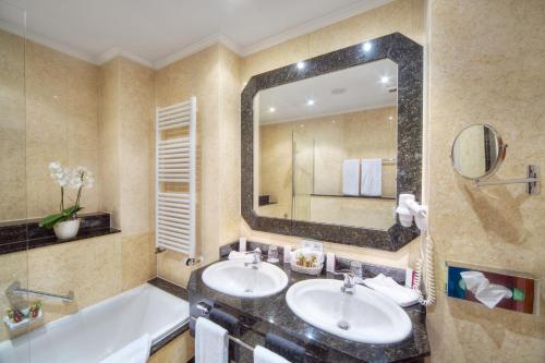 a bathroom with two sinks and a large mirror at Häcker's Hotel in Bad Ems