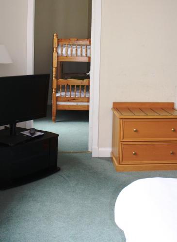 a room with a bed and a dresser and a television at Peebles Hydro in Peebles