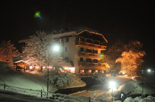a large building at night with snow and lights at Rauzi Hotel Garnì & apartments in Malè