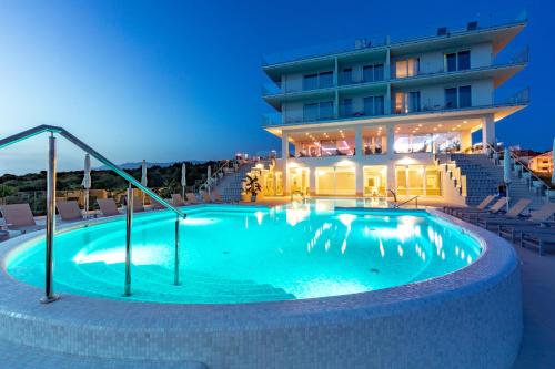 a swimming pool in front of a building at Hotel In Excelsis in Novalja