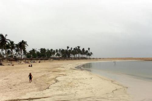 a person walking on a beach near the water at NOOR PLAZA BEACH FURNISHED FLATS in Salalah