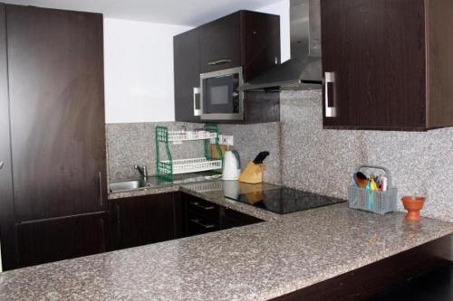 a kitchen with brown cabinets and a counter top at NOOR PLAZA BEACH FURNISHED FLATS in Salalah