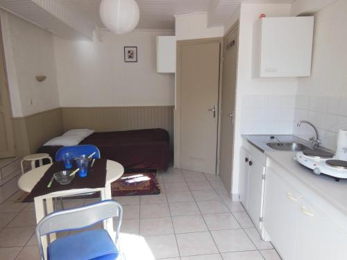 eine kleine Küche mit einem Tisch, Stühlen und einem Bett in der Unterkunft studio bord de mer, SAINT MALO in Saint-Malo
