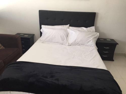 uma cama com lençóis e almofadas brancos e duas mesas de cabeceira em COSY STUDIO APARTMENT GREAT LOCATION (203) em Bogotá
