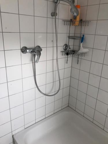 a shower in a white tiled bathroom with a sink at Einzel-Apartment Düsseldorf Oberkassel in Düsseldorf