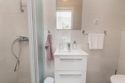 a white bathroom with a sink and a shower at Apartments Lidija in Cavtat