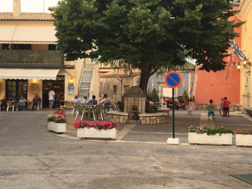 a street with a tree and some people and flowers at ELIA in Doukádes