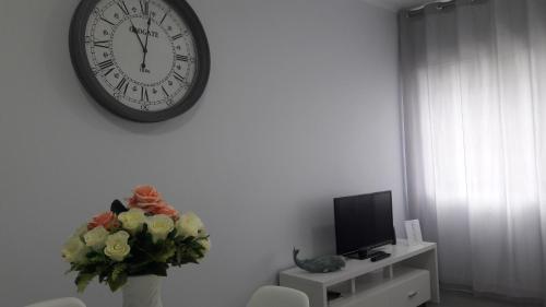 a clock on a wall with a vase of flowers and a tv at AL - BOA NOVA in Madalena