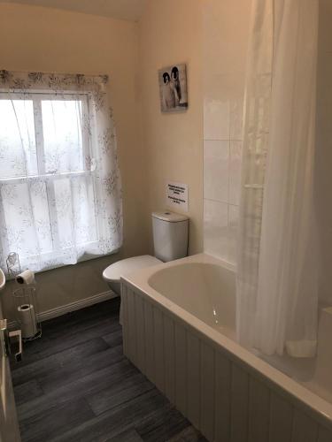 a bathroom with a bath tub and a window at Gilmore House in Ardglass
