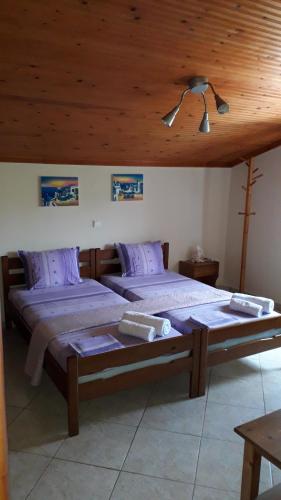 a bedroom with two beds and a wooden ceiling at HOUSE DILENA TSIMTSIRI in Limenaria