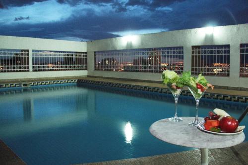 a pool with a table with a plate of fruit and drinks at Like Ü Hotel Goiânia in Goiânia