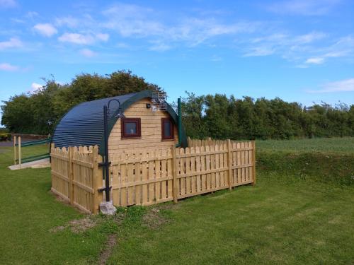 a small wooden house with a fence in a field at shanagarry / Ballycotton Glamping pod in Cork