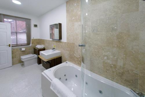 a bathroom with a tub and a toilet and a sink at Three Queens Hotel in Burton upon Trent