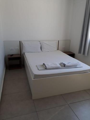 Una cama blanca con sábanas blancas y almohadas. en Hotel Lisboa en Curitiba
