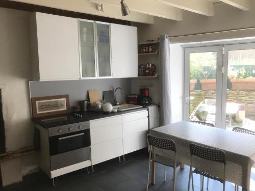 une cuisine avec des armoires blanches et une table avec des chaises dans l'établissement Ker Iliz, à Locquirec