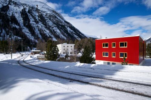 a red building next to a snow covered mountain at Hotel Morteratsch in Pontresina