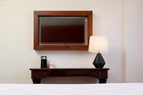 a television on a wall with a table with a lamp at Holiday Inn Hotel & Suites Centro Historico by IHG in Guadalajara