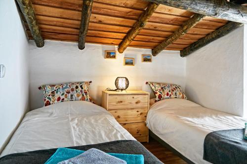Dos camas en una habitación con techos de madera. en Recanto do Telheiro, en Monsaraz