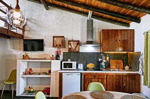 Una cocina con gabinetes de madera y una mesa con sillas. en Recanto do Telheiro, en Monsaraz