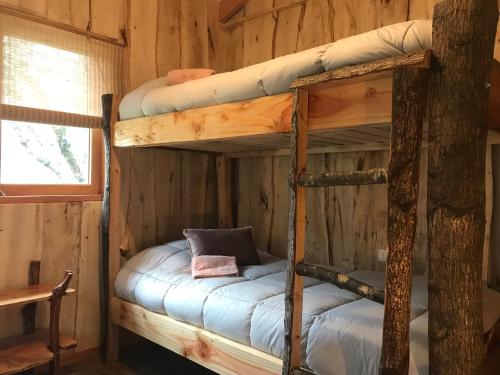 a bedroom with two bunk beds in a log cabin at Karkú Lodge in Pucón