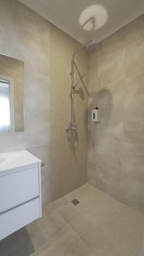 a bathroom with a shower with a white sink and a shower at Vila Milreu Guest House in Estói
