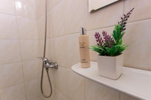ein Badezimmer mit einem Regal mit einer Flasche Seife und Blumen in der Unterkunft PD Hostel in Dunaújváros