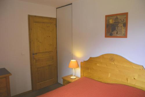 - une chambre dotée d'un lit en bois avec une lampe et une porte dans l'établissement Appt 4 /5 pers - 3 min. centre ville, à Chamonix-Mont-Blanc